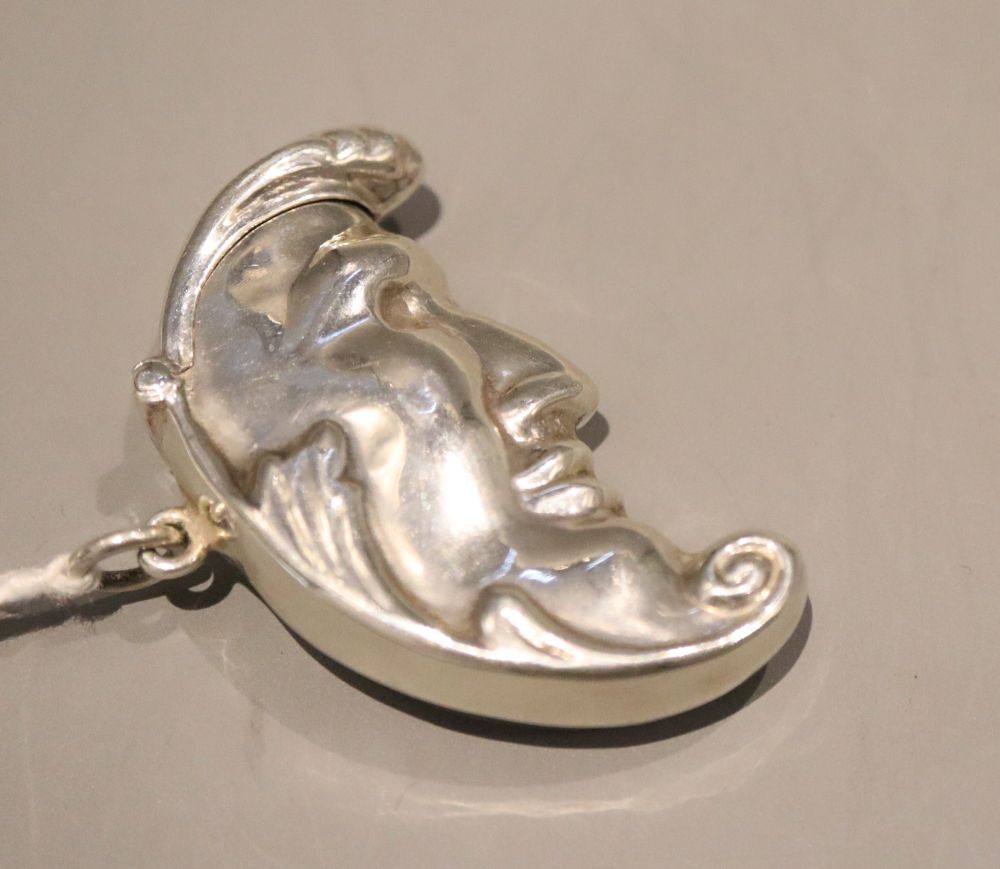 A modern 925 pill box, modelled as a crescent shaped face, with hinged lid, 49mm.